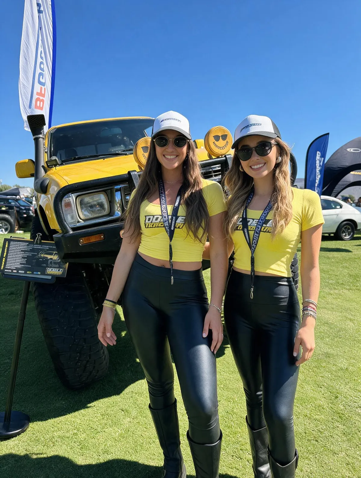 Dos anfitrionas de Doble Tracción junto a un vehículo todoterreno en evento automotriz.