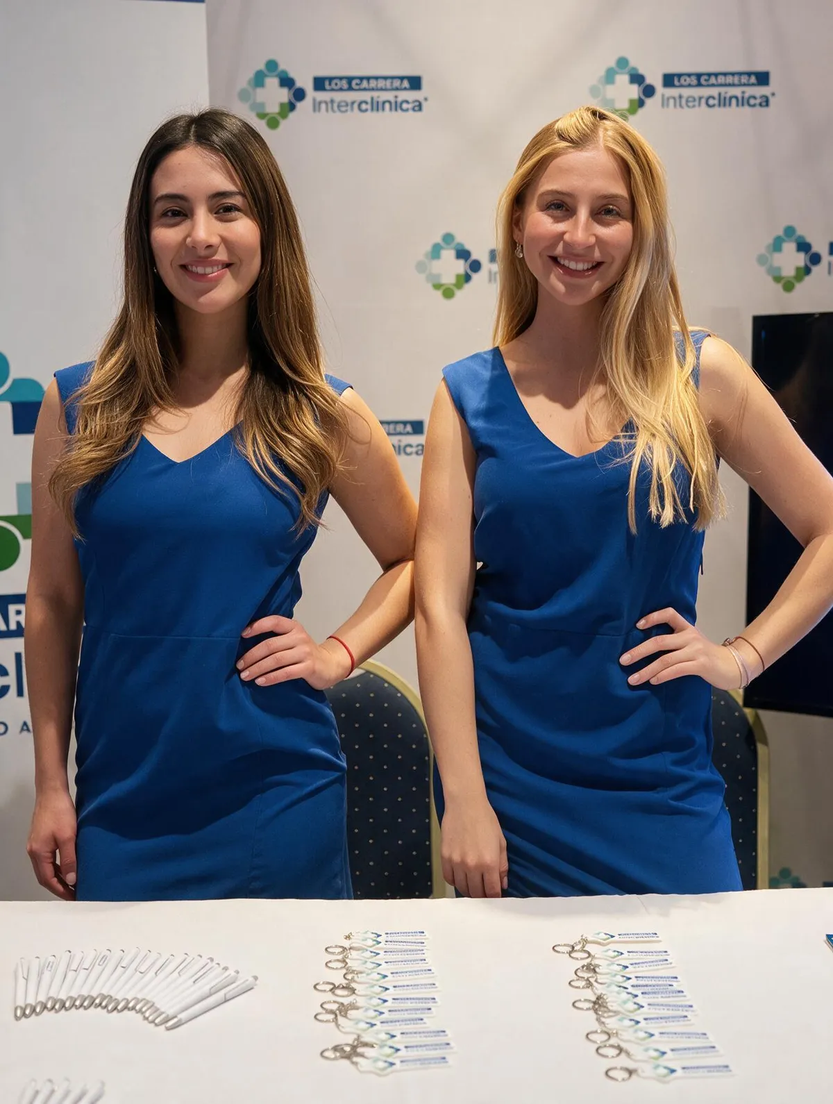 Dos anfitrionas con vestuario azul en evento de Clínica Luis Carrera.